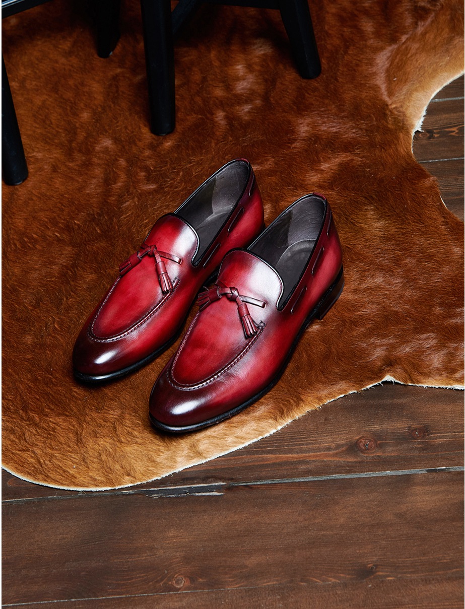 Red tassel loafers on a cowhide rug