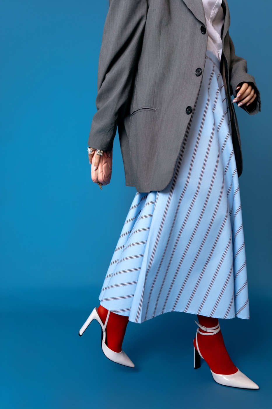 Grey tailored blazer over a striped skirt with red socks and white pumps