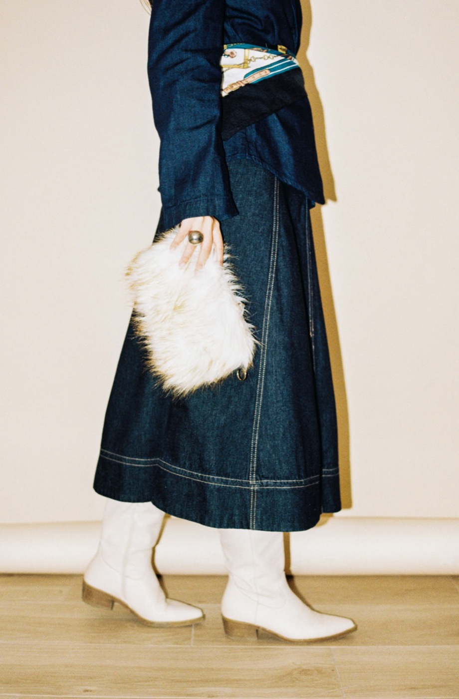 Denim maxi skirt styled with a shearling clutch and white boots